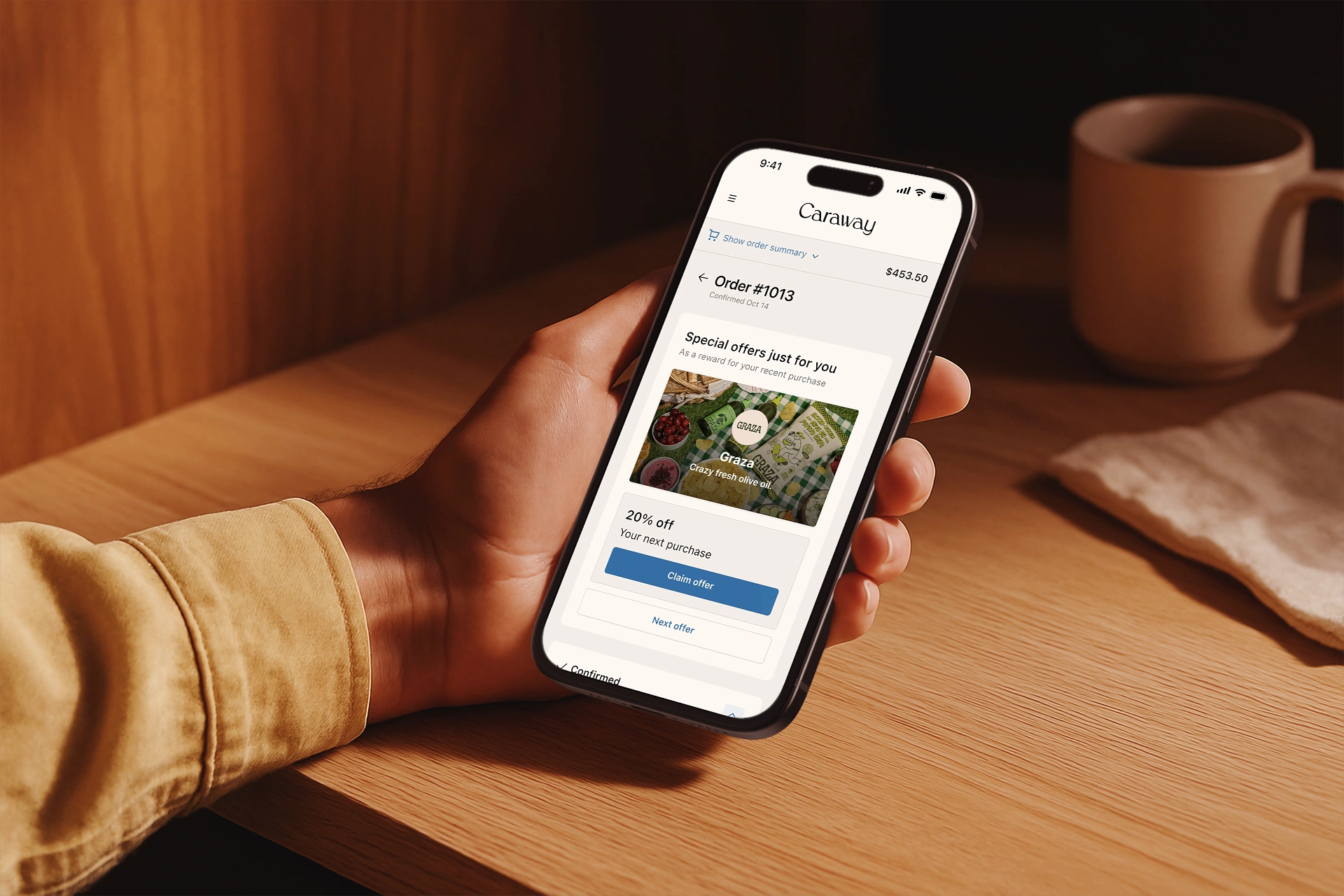 A hand holding a phone over a wooden table. On screen, a Caraway order confirmation carries one post-purchase offer tied to the purchase just made: 20% off the next order. Part of a case study on The Disco Experience.